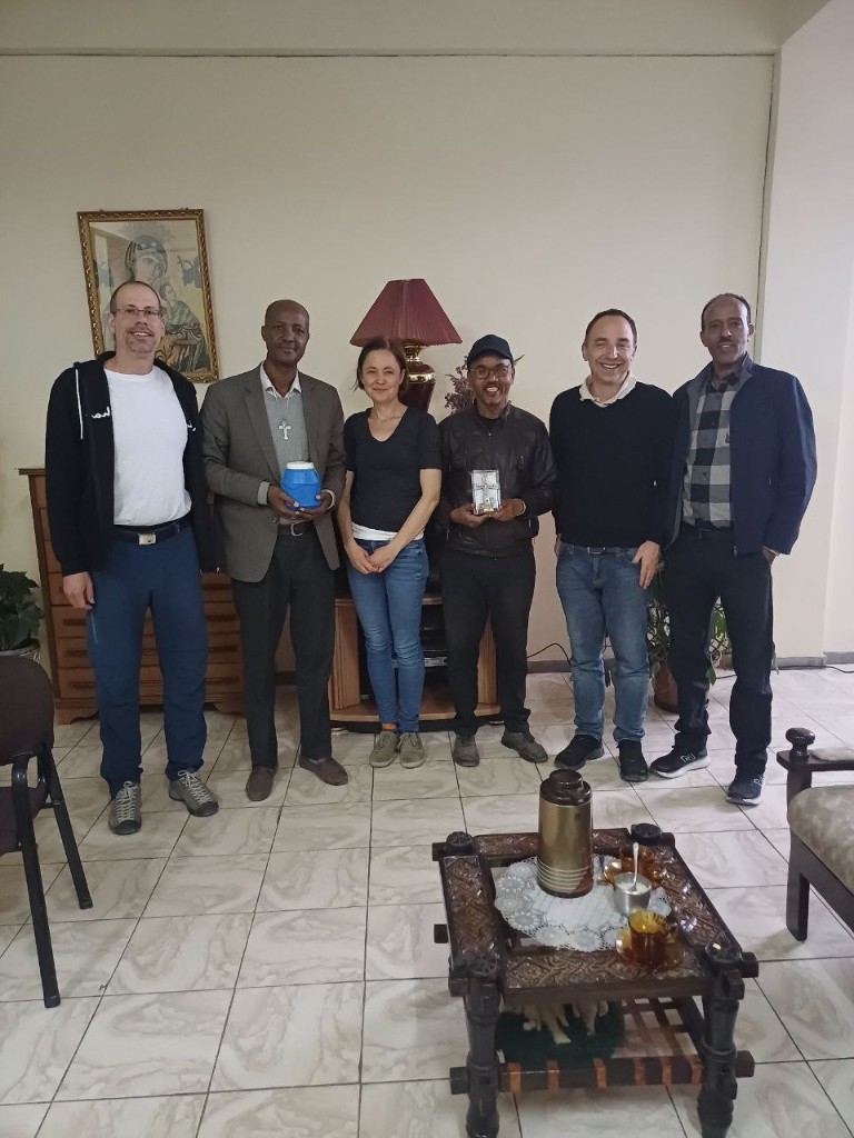 Six team members standing together indoors; two colleagues hold small awards.